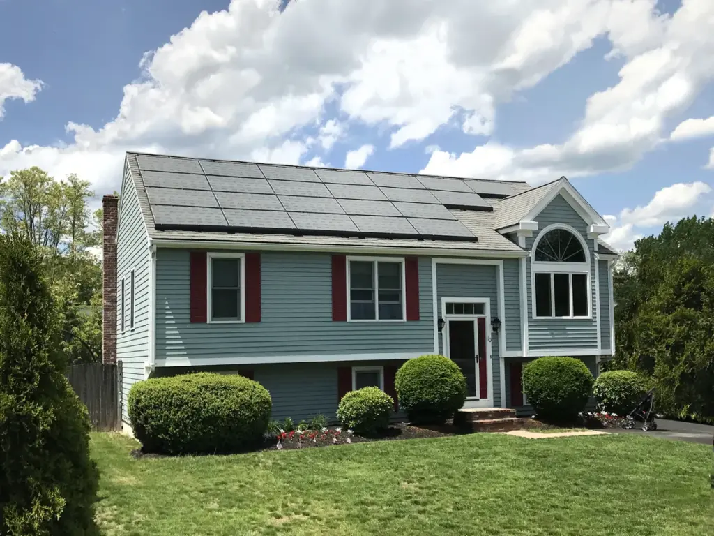 A suburban house with solar panels on the roof under a blue sky